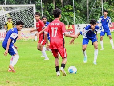Pemain Pra PORA Aceh Besar (kaos biru) mencoba saling merebut bola dari pemain Pra PORA Banda Aceh dalam laga uji coba di Lapangan Bola Amla, Kecamatan Ingin Jaya, Aceh Besar, Sabtu (21/06/2025) sore. FOTO/MC ACEH BESAR