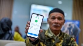 Seorang pensiunan memamerkan aplikasi autentifikasi nasabah PT Taspen. (Foto: ANTARA FOTO