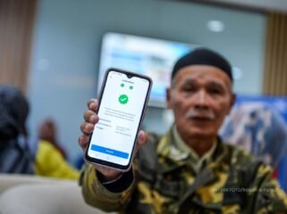 Seorang pensiunan memamerkan aplikasi autentifikasi nasabah PT Taspen. (Foto: ANTARA FOTO