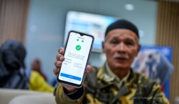 Seorang pensiunan memamerkan aplikasi autentifikasi nasabah PT Taspen. (Foto: ANTARA FOTO