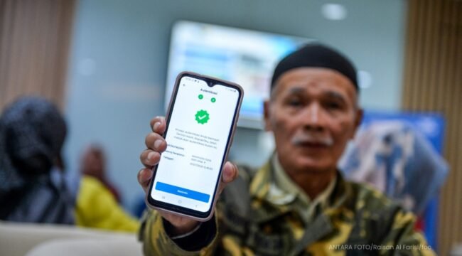 Seorang pensiunan memamerkan aplikasi autentifikasi nasabah PT Taspen. (Foto: ANTARA FOTO