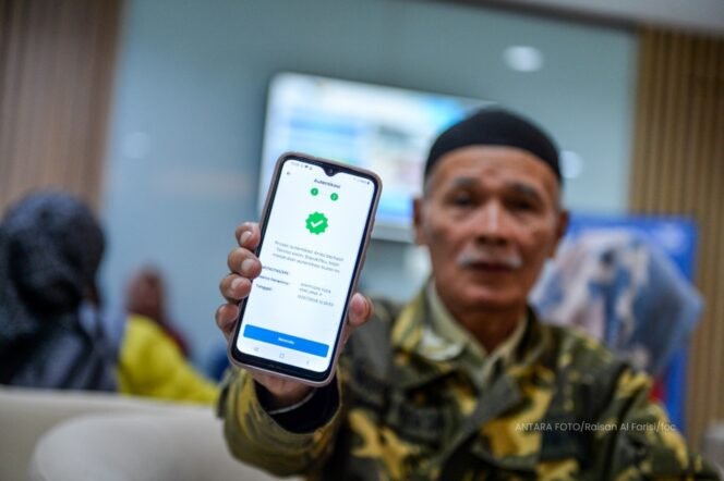 
					Seorang pensiunan memamerkan aplikasi autentifikasi nasabah PT Taspen. (Foto: ANTARA FOTO