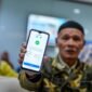 Seorang pensiunan memamerkan aplikasi autentifikasi nasabah PT Taspen. (Foto: ANTARA FOTO