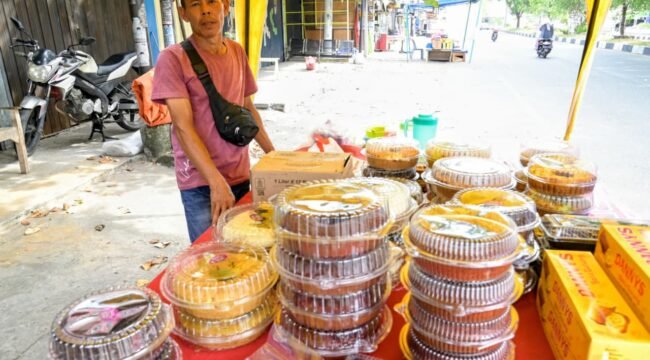 Hasan (48) pedagang berbagai jenis kue bolu di Pasar Lambaro, Kecamatan Ingin Jaya, Aceh Besar , Senin (23/03/2026). FOTO/MC ACEH BESAR
